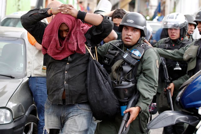 An anti-government protesters are detained by national guard after clash with guard at end of march in Caracas