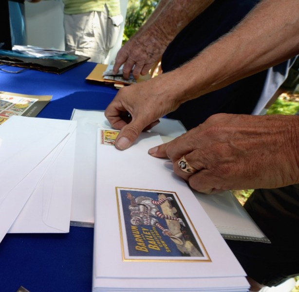 Un invitado en el Servicio Postal de EE.UU. ceremonia de primer día de la emisión de las nuevas Posters Vintage Circus Sellos para siempre pone un sello en un sobre conmemorativo ( AFP)