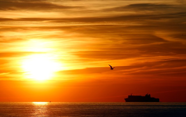 A passenger ferry sails during sunset off the coast of Marseille