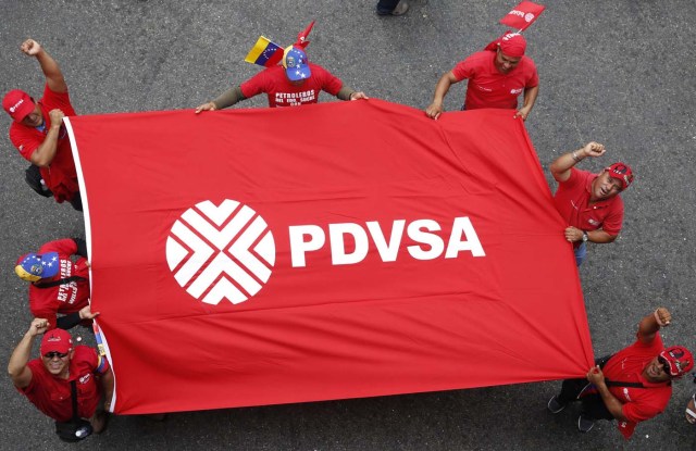 Workers of state-run oil company PDVSA shout and hold a flag with their corporate logo during a rally against imperialism in Caracas