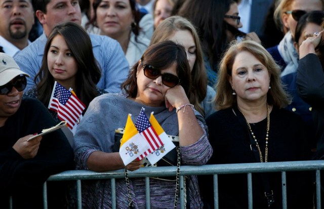 A woman holds U.S. and Vatican flags as people gather ahead of Pope Francis' meeting with U.S. President Barack Obama outside the White House in Washington September 23, 2015. REUTERS/Kevin Lamarque TPX IMAGES OF THE DAY