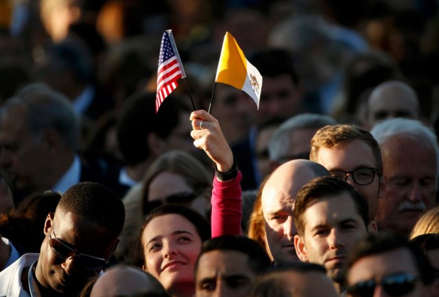  woman holds U.S. and Vatican flags as people gather ahead of Pope Francis' meeting with U.S. President Barack Obama outside the White House in Washington September 23, 2015. REUTERS/Kevin Lamarque