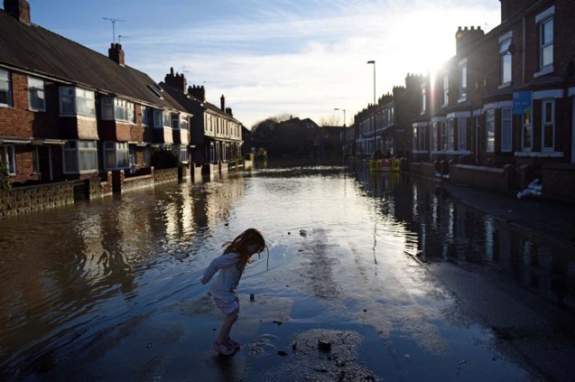 A girl plays in floodwater on residential street adjacent to the River Foss which burst its banks in York, northern England, on December 27, 2015. Britain's government was holding emergency talks Sunday as flooding in northern England forced hundreds of people to leave their homes, including in the historic tourist destination of York. AFP PHOTO / OLI SCARFF / AFP / OLI SCARFF