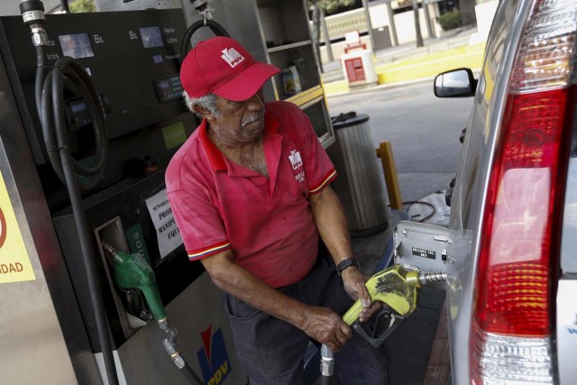 A worker pumps fuel into a vehicle at a gas station which belongs to PDVSA in Caracas, Venezuela February 19, 2016. REUTERS/Marco Bello
