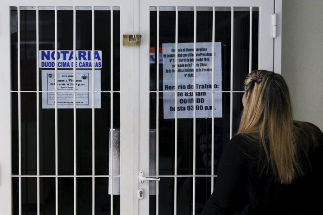 A woman reads a sign at the door of a closed notary office in Caracas, April 8, 2016. REUTERS/Marco Bello