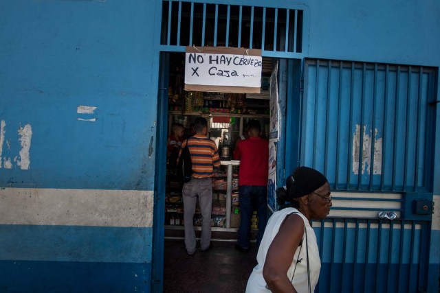 ACOMPAÑA CRÓNICA:VENEZUELA EMPRESAS CAR01. CARACAS (VENEZUELA), 11/05/2016.- Fotografía del 6 de mayo de 2016 de una mujer caminando frente a una licorera ubicada en Catia, con un letrero en la entrada donde se lee "No hay cerveza x caja gracias" en la ciudad de Caracas (Venezuela). Los trabajadores de Empresas Polar, principal productora privada de alimentos en Venezuela y responsable del 80 % de la industria cervecera en el país, se encuentran custodiando las cuatro plantas productoras de cerveza porque temen que el Gobierno tome las instalaciones. Las plantas cerveceras de esa empresa tienen una nueva fachada de quejas contra el Gobierno de Nicolás Maduro mientras bares y restaurantes hacen malabares para ofrecer el producto. EFE/MIGUEL GUTIERREZ