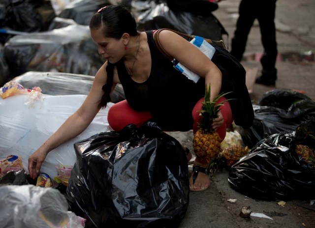 En esta foto del 2 de junio de 2016, una mujer embarazada que pidió no ser identificada recoge fruta en el basural del mercado Coche en Caracas, Venezuela. Productos básicos como la harina y el aceite de cocina están subsidiados y cuestan centavos, pero frutas y verduras se han convertido en un lujo fuera del alcance de muchas familias venezolanas. (AP Foto/Fernando Llano)