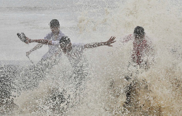 Los hombres se empapan por una gran ola durante la marea alta en la primera línea de mar en Mumbai, India, 23 de junio de 2016. REUTERS / Shailesh Andrade