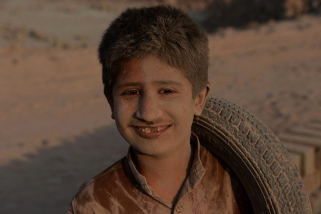 In this photograph taken on July 27, 2016, an Afghan boy poses for a photograph along a dusty road on the outskirts of Jalalabad. / AFP PHOTO / NOORULLAH SHIRZADA