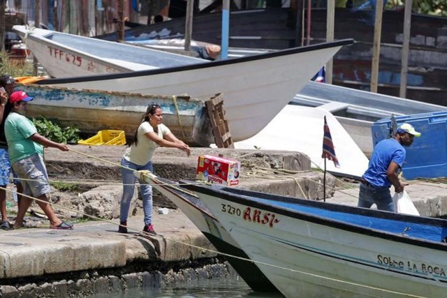 Venezolanos cargan en un bote mercancías, que son escasas en su país, mientras se preparan para volver a casa desde el puerto de San Fernando, al sur de Trinidad. Foto tomada el 15 de junio del 2016. REUTERS/Andrea De Silva