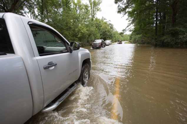 Vehicles navigate through the remaining floodwaters on Liberty Road in Greenwell Springs Louisiana, U.S., August 14, 2016. REUTERS/Jeffrey Dubinsky