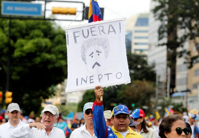 An opposition supporter takes part in a rally to demand a referendum to remove Venezuela's President Nicolas Maduro while carrying a sign that reads "Go out, inept" in Caracas, Venezuela, September 1, 2016. REUTERS/Christian Veron