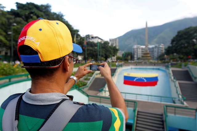 An opposition supporter wearing a cap with the colours of the national flag, takes a photo with his cell phone during a rally to demand a referendum to remove Venezuela's President Nicolas Maduro in Caracas, Venezuela, September 1, 2016. REUTERS/Christian Veron