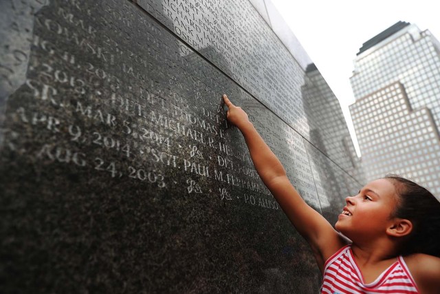NEW YORK, NY - SEPTEMBER 09: Gabriella Ortiz reaches up to point to the name of her grandfather fallen New York City Police officer Edwin Ortiz at a wall commemorating fallen officers on September 9, 2016 in New York City. Families gathered at the wall following a procession in Lower Manhattan to mark the 15th anniversary of the 9/11 attacks and the officers who were killed during and after the event. Detective Ortiz died from illnesses he contracted from inhaling toxic materials during the rescue and recovery operations at Ground Zero. Spencer Platt/Getty Images/AFP
