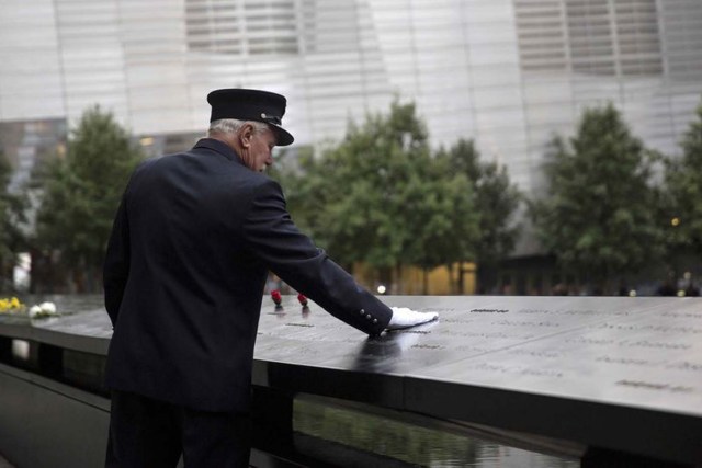 A member of the New York Fire Department places his hand on the memorial before a ceremony marking the 14th anniversary of the 9/11 attacks, at the National September 11 Memorial and Museum in Lower Manhattan in New York September 11, 2015. REUTERS/Andrew Kelly/File Photo