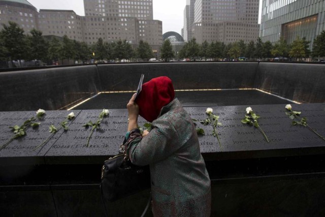 A woman places white roses at the National September 11 Memorial and Museum in Lower Manhattan in New York, September 10, 2015. REUTERS/Andrew Kelly/File Photo