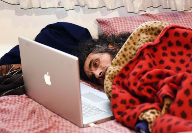 El sirio Abu Wa'el Dhiab, un ex detenido de Guantánamo, descansa en la cama mientras conversa con su familia a través de un ordenador portátil en su apartamento en Montevideo, Uruguay, el viernes 9 de septiembre de 2016. (AP Foto/Matilde Campodonico)