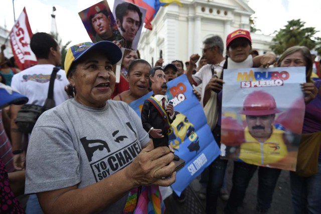 Supporters of Venezuelan President Nicolas Maduro, demonstrate outside the National Assembly during an extraoridinary session called by opposition leaders, in Caracas on October 23, 2016. The opposition Democratic Unity Movement (MUD) called a Parliamentary session to debate putting President Nicolas Maduro on trial to "restore democracy" in an emergency session that descended into chaos as supporters of the leftist leader briefly seized the chamber. / AFP PHOTO / JUAN BARRETO