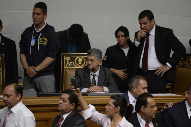 The president of the Venezuelan National Assembly, Henry Ramos Allup (C) observes as supporters of Venezuelan President Nicolas Maduro force their way to the National Assembly during an extraordinary session called by opposition leaders, in Caracas on October 23, 2016. The opposition Democratic Unity Movement (MUD) called a Parliamentary session to debate putting President Nicolas Maduro on trial to "restore democracy" in an emergency session that descended into chaos as supporters of the leftist leader briefly seized the chamber. / AFP PHOTO / FEDERICO PARRA