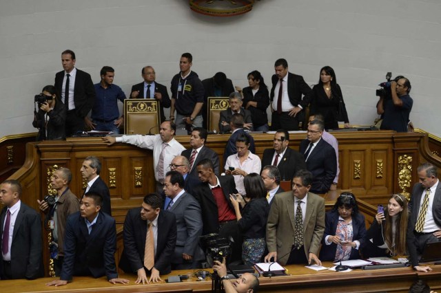 The president of the Venezuelan National Assembly, Henry Ramos Allup (C-up) observes as supporters of Venezuelan President Nicolas Maduro force their way to the National Assembly during an extraordinary session called by opposition leaders, in Caracas on October 23, 2016. The opposition Democratic Unity Movement (MUD) called a Parliamentary session to debate putting President Nicolas Maduro on trial to "restore democracy" in an emergency session that descended into chaos as supporters of the leftist leader briefly seized the chamber. / AFP PHOTO / FEDERICO PARRA