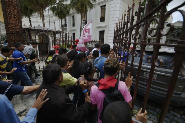 Supporters of Venezuelan President Nicolas Maduro break the gate and force their way to the National Assembly during an extraoridinary session called by opposition leaders, in Caracas on October 23, 2016. The Democratic Unity Movement(MUD), opposite to Nicolas Maduro's government called a Parliamentary session to discuss restructuring of the Boliviarian Republic of Venezuela's Constitution, the constitutional order and democracy as main issues. Demonstrators outside the building forced their entrance to interrupt the debate and the session was suspended. / AFP PHOTO / JUAN BARRETO