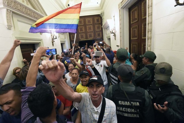 Supporters of Venezuelan President Nicolas Maduro force their way to the National Assembly during an extraoridinary session called by opposition leaders, in Caracas on October 23, 2016. The Democratic Unity Movement(MUD), opposite to Nicolas Maduro's government called a Parliamentary session to discuss restructuring of the Boliviarian Republic of Venezuela's Constitution, the constitutional order and democracy as main issues. Demonstrators outside the building forced their entrance to interrupt the debate and the session was suspended. / AFP PHOTO / JUAN BARRETO