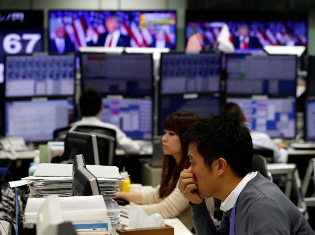 Employees of a foreign exchange trading company work near monitors showing U.S. President-elect Donald Trump speaking on TV news (top) in Tokyo, Japan, November 9, 2016. REUTERS/Toru Hanai