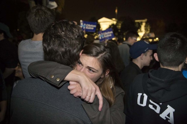 MHR33 WASHINGTON (EE.UU.), 09/11/2016.- Una pareja simpatizante de la candidata presidencial demócrata, Hillary Clinton, se abraza entre un grupo de personas reunidas frente a la Casa Blanca en Washington DC, Estados Unidos, hoy, 9 de noviembre de 2016. El rival de Clinton, el republicano Donald Trump, ha ganado hoy las elecciones presidenciales en Estados Unidos y tomará posesión se su cargo en enero. EFE/Michael Reynolds