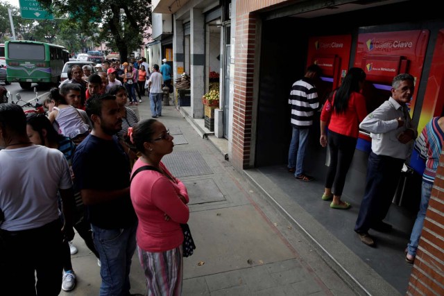 People line up to withdraw cash from an automated teller machine (ATM) outside a Banco de Venezuela branch in Caracas, Venezuela November 25, 2016. Picture taken November 25, 2016. REUTERS/Marco Bello
