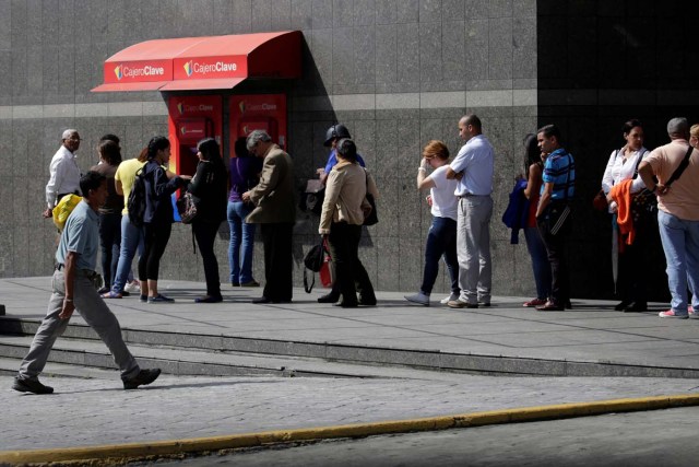 People line up to withdraw cash from an automated teller machine (ATM) outside a Banco de Venezuela branch in Caracas, Venezuela November 23, 2016. Picture taken November 23, 2016. REUTERS/Marco Bello
