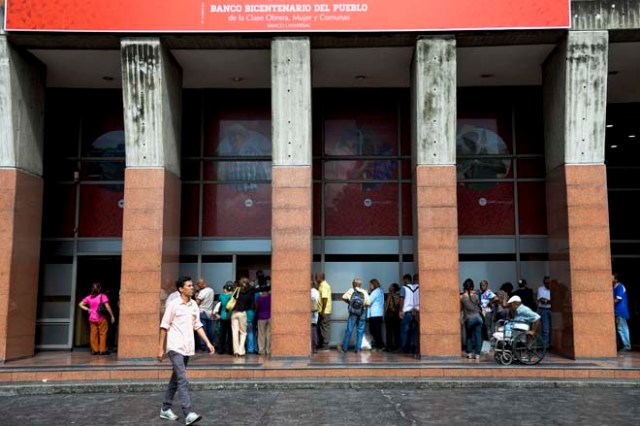 People queue to withdraw money from an automated teller machine (ATM) in Caracas on December 1, 2016. Venezuelan banks guaranteed their continued operation, after rumors about a close in December to adjust to an alleged issuance of bills of higher denomination. At the moment, the note of highest denomination is the one of 100 bolivars, that is just enough to buy a sweet. / AFP PHOTO / Federico PARRA