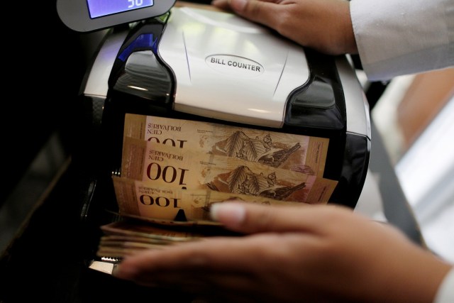 A cashier counts Venezuelan bolivar notes with a machine inside a restaurant in downtown Caracas, Venezuela, December 12, 2016. REUTERS/Ueslei Marcelino