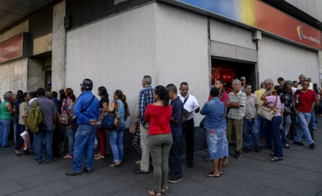 People queue outside a bank in Caracas in an attempt to deposit money, on December 13, 2016. Venezuelan President Nicolas Maduro ordered on December 12 the border with Colombia sealed for 72 hours, accusing US-backed "mafias" of conspiring to destabilize his country's economy by hoarding bank notes. The closure came a day after Maduro signed an emergency decree removing Venezuela's largest bank note, the 100 bolivar bill, from circulation because of what he called a Washington-sponsored plot against his country's troubled economy. / AFP PHOTO / FEDERICO PARRA