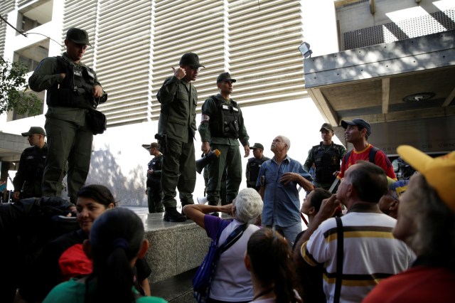 Venezuelan National Guard members control the crowd as people queue to deposit their 100 bolivar notes, outside Venezuela's Central Bank in Caracas, Venezuela December 16, 2016. REUTERS/Marco Bello