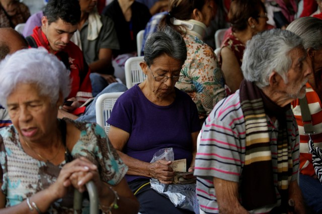 A woman counts 100 bolivar notes as she queues to deposit them, outside Venezuela's Central Bank in Caracas, Venezuela December 16, 2016. REUTERS/Marco Bello