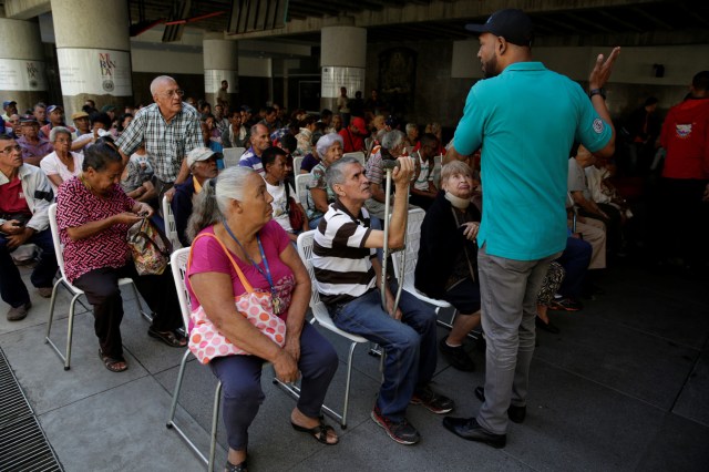 A man explains to the queuing people the process of depositing 100 bolivar notes, outside Venezuela's Central Bank in Caracas, Venezuela December 16, 2016. REUTERS/Marco Bello