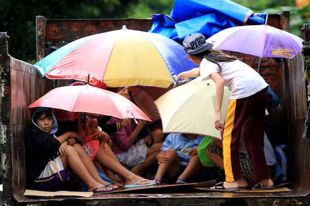 Young residents sit in a truck after the local government implemented preemptive evacuations at Barangay Matnog, Daraga, Albay province on December 25, 2016, due to the approaching typhoon Nock-Ten. Babies, toddlers and old people were loaded onto military trucks in the Philippines on December 25 as thousands fled from the path of a powerful typhoon barrelling towards the disaster-prone archipelago. / AFP PHOTO
