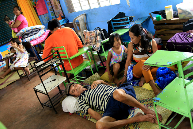 Residents sit inside a classroom at the Central Elementary School which was turned into an evacuation centre in Santo Domingo, Albay province on December 25, 2016 due to approaching Typhoon Nock-Ten. Thousands of residents were fleeing coastal and other hazardous areas in the eastern Philippines on December 25 as a powerful typhoon barrelled towards the disaster-prone archipelago. / AFP PHOTO / CHARISM SAYAT