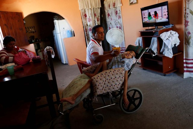 Miguel Anton (C) feeds his son Jose Gregorio Anton, 11, a neurological patient being treated with anticonvulsants, at their house in La Guaira, Venezuela February 20, 2017. REUTERS/Carlos Garcia Rawlins    SEARCH "EPILEPSY CARACAS" FOR THIS STORY. SEARCH "WIDER IMAGE" FOR ALL STORIES.