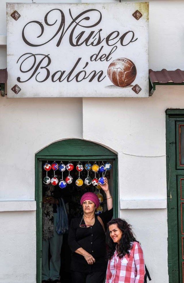 Tourists pose for pictures at the entrance of the Museum of the Soccer Ball in Mongui, in the Colombian department of Boyaca, on February 13, 2017. Mongui, in the central mountains of Colombia, has about 20 football factories that make balls mainly for football and micro-football. About a quarter of the town's 4,900 inhabitants work in these factories. / AFP PHOTO / Luis ACOSTA