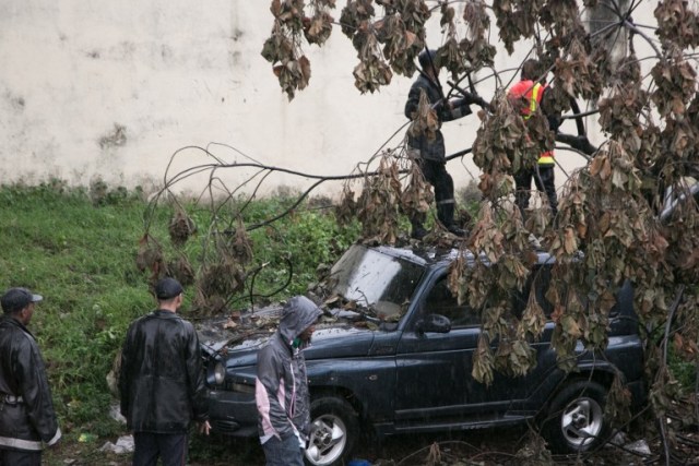 Malagasy firefighters work to remove a fallen tree from a car caused by tropical cyclone Enawo in Antananarivo, Madagascar, on March 8, 2017. At least four people have been killed by tropical cyclone Enawo in Madagascar, the prime minister said on March 8, 2017, as the storm tracked towards the capital Antananarivo threatening severe flooding. / AFP PHOTO / RIJASOLO