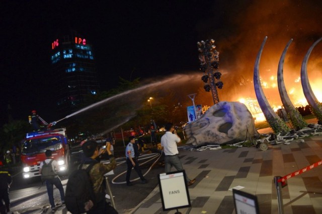 This picture taken on March 9, 2017 shows firefighter truck injecting water to control a fire on a giant model of King Kong during the premiere of the "Kong: Skull Island" in Ho Chi Minh City. Film buffs with the hottest ticket in town were left running for safety after a giant model of King Kong went up in flames at the sizzling Vietnam premiere of the rebooted horror classic. / AFP PHOTO / STR
