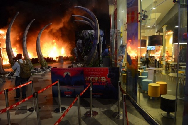 This picture taken on March 9, 2017 shows photographer taking picture of a fire on a giant model of King Kong during the premiere of the "Kong: Skull Island" in Ho Chi Minh City. Film buffs with the hottest ticket in town were left running for safety after a giant model of King Kong went up in flames at the sizzling Vietnam premiere of the rebooted horror classic. / AFP PHOTO / STR