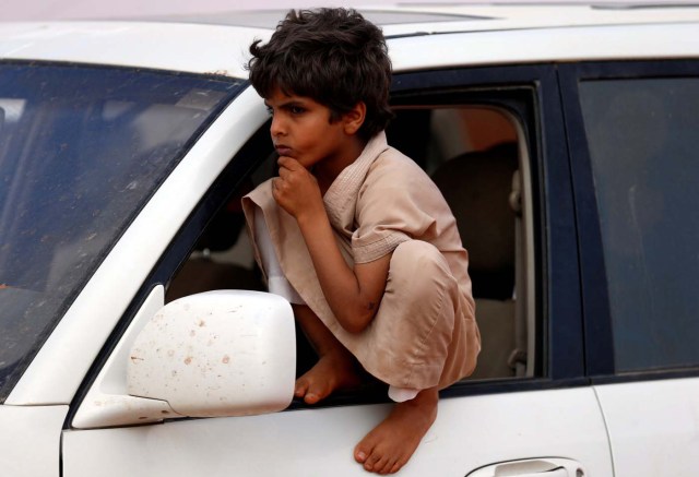 A boy sits by a car as he looks at camels during the King Abdulaziz Camel Festival in Rimah Governorate, north-east of Riyadh, Saudi Arabia March 29, 2017. REUTERS/Faisal Al Nasser