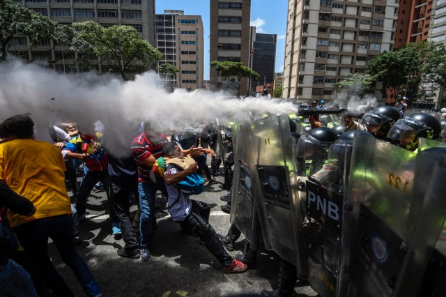 Venezuela's opposition activists clash with riot police agents during a protest against Nicolas Maduro's government in Caracas on April 4, 2017. Protesters clashed with police in Venezuela Tuesday as the opposition mobilized against moves to tighten President Nicolas Maduro's grip on power. Protesters hurled stones at riot police who fired tear gas as they blocked the demonstrators from advancing through central Caracas, where pro-government activists were also planning to march.  / AFP PHOTO / JUAN BARRETO