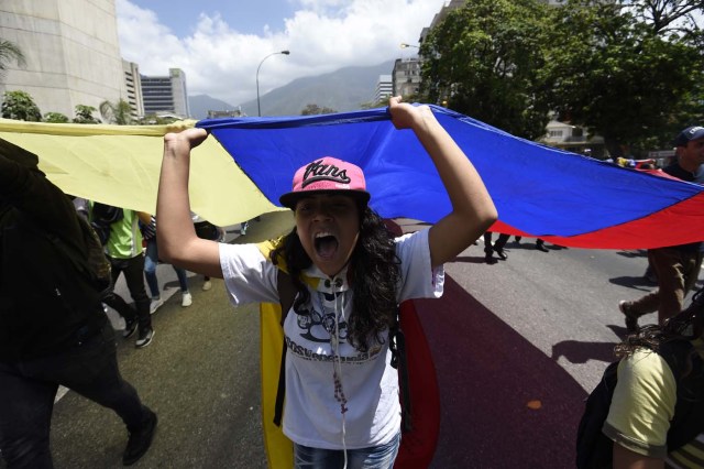 Venezuelan opposition activists shout slogans during a protest against the government of President Nicolas Maduro on April 6, 2017 in Caracas. The center-right opposition vowed fresh street protests -after earlier unrest left dozens of people injured - to increase pressure on Maduro, whom they blame for the country's economic crisis. / AFP PHOTO / JUAN BARRETO