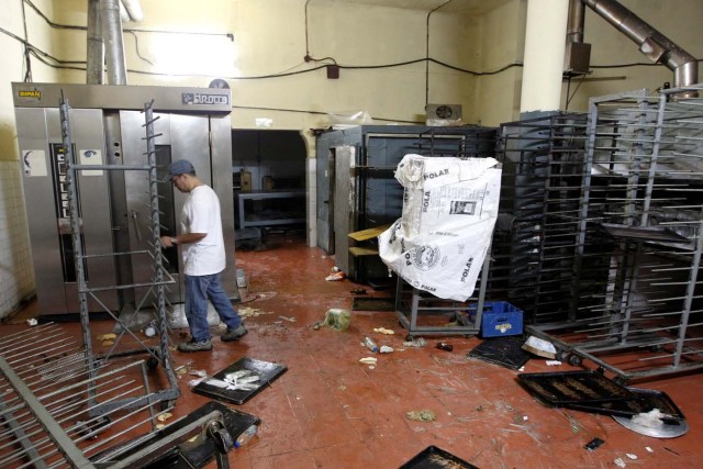 A worker walks next to damaged goods and empty shelves in a bakery, after it was looted in Caracas, Venezuela April 20, 2017. REUTERS/Christian Veron