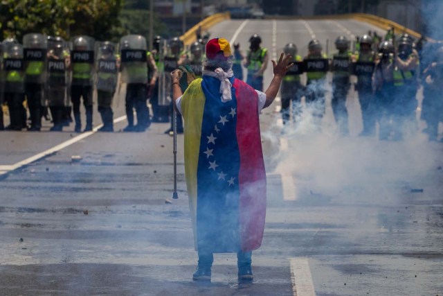 CAR01. CARACAS (VENEZUELA), 26/04/2017.- Un venezolano portando la bandera nacional hace frente a los miembros de la Policía Nacional Bolivariana que detienen el paso de una manifestación hoy, miércoles 26 de abril de 2017, en Caracas (Venezuela). Las fuerzas de seguridad de Venezuela dispersaron nuevamente algunas de las marchas convocadas por la oposición en Caracas, que pretendían llegar a la sede principal de la Defensoría del Pueblo en el centro de la capital. EFE/MIGUEL GUTIÉRREZ