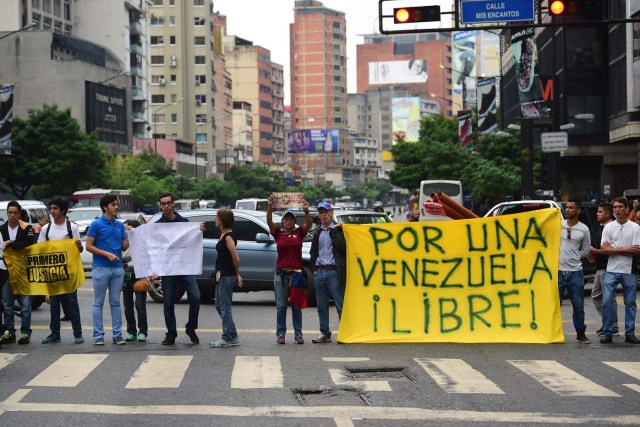 Demonstrators display a banner as they block a street during a protest against Venezuelan President Nicolas Maduro in Caracas, on May 2, 2017. Venezuelan President Nicolas Maduro called for a new constitution Monday as he fights to quell a crisis that has led to more than a month of protests against him and deadly street violence. The opposition slammed the tactic as a "coup d'etat" and urged protesters to "block the streets" from Tuesday. It said it was organizing a "mega protest" for Wednesday. / AFP PHOTO / RONALDO SCHEMIDT
