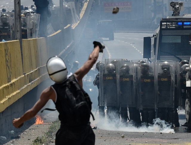 Opposition activists clash with riot police during a protest against President Nicolas Maduro in Caracas, on May 10, 2017. Venezuelan protesters hit the streets on Wednesday armed with "Poopootov cocktails," jars filled with excrement which they vowed to hurl at police as a wave of anti-government demonstrations turned dirty. / AFP PHOTO / CARLOS BECERRA